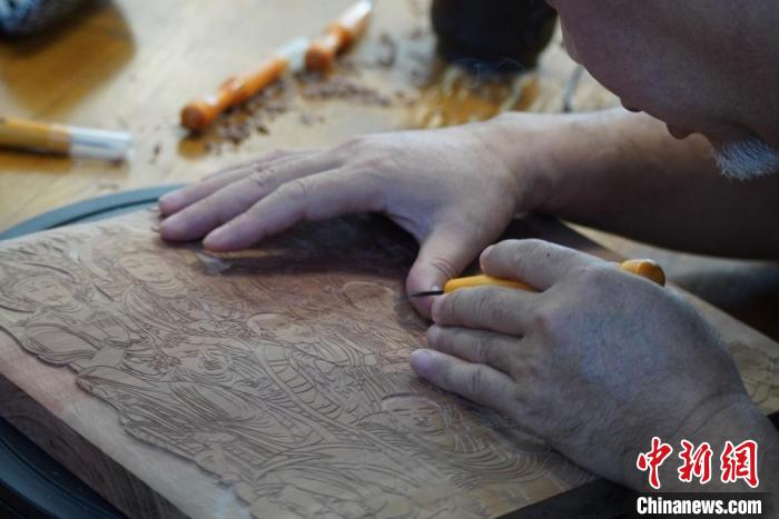 圖為徐晉林湊近木板，近距離制作雕版畫(huà)?！【琶赖┰?　攝