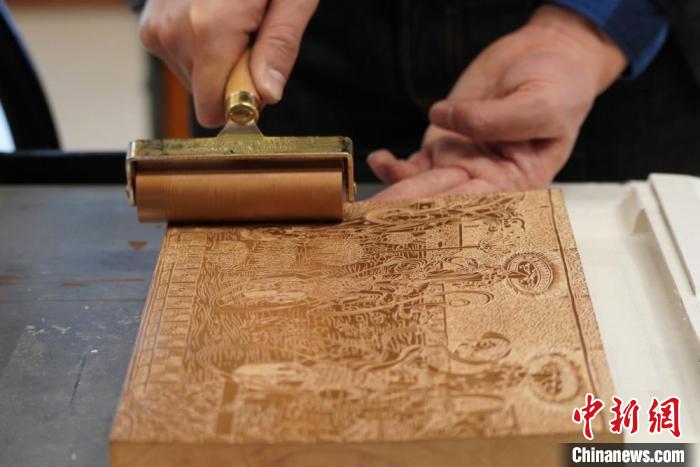 圖為徐晉林工作室工作人員正在給雕好壁畫(huà)的版面滾油墨?！【琶赖┰?　攝