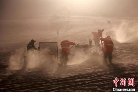 圖為敦煌市鳴沙山月牙泉景區(qū)“駱駝保姆”清理駱駝糞便?！垥粤?攝
