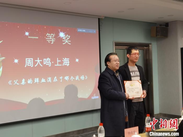 圖為作家、西北師范大學(xué)新聞與傳媒學(xué)院院長(zhǎng)徐兆壽頒發(fā)一等獎(jiǎng)證書(shū)，代領(lǐng)獎(jiǎng)?wù)呱吓_(tái)領(lǐng)獎(jiǎng)?！钅?攝