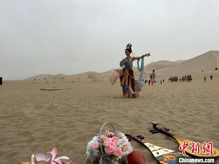 圖為2023年4月底，敦煌大漠“逐舞者”奧楠在鳴沙山月牙泉景區(qū)視頻直播敦煌舞?！●T志軍 攝