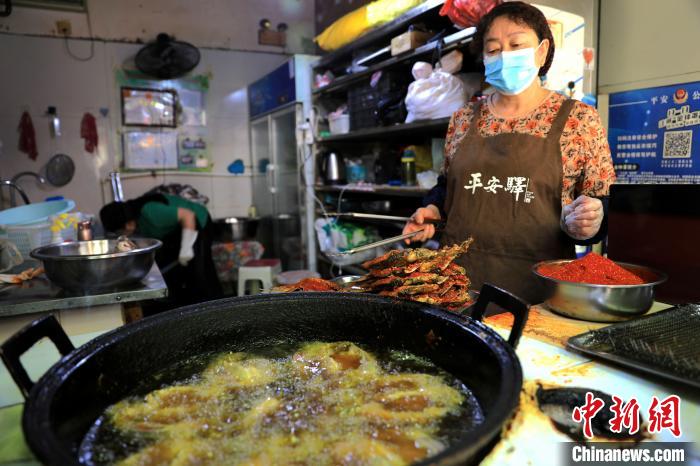 圖為平安驛·河湟民俗文化體驗地內(nèi)的商戶炸干板魚。　薛蒂 攝