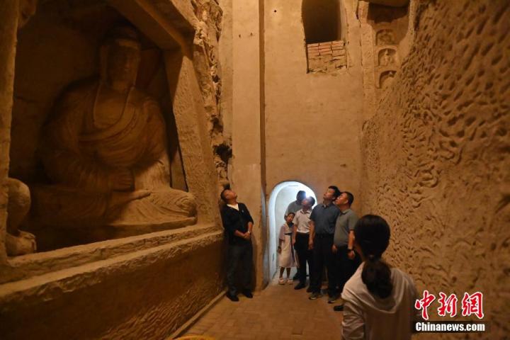 7月15日，游人參觀甘肅省平涼市涇川縣百里石窟長廊中的王母宮石窟。百里石窟長廊位于涇川縣境內，由512個石窟、5眼窟中石井組成，現存王母宮石窟、鳳凰山石窟、南石窟寺、丈八寺石窟、羅漢洞石窟、太山寺石窟等規(guī)模較大的石窟群，還有數量眾多的小石窟群。王母宮石窟又名千佛洞，該窟設計宏大，造像生動，窟內擁有造像數百尊，是較為珍貴的佛教文化歷史遺存。中新社記者 李亞龍 攝</p>
<p>