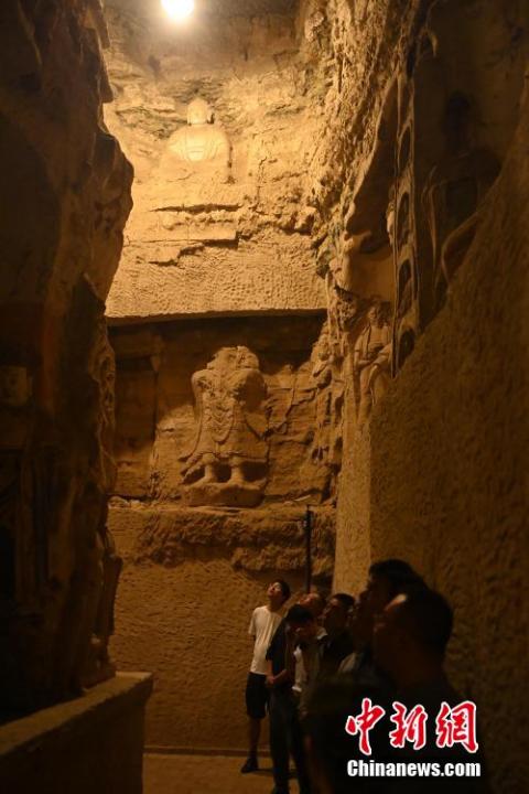7月15日，游人參觀甘肅省平涼市涇川縣百里石窟長廊中的王母宮石窟。百里石窟長廊位于涇川縣境內，由512個石窟、5眼窟中石井組成，現存王母宮石窟、鳳凰山石窟、南石窟寺、丈八寺石窟、羅漢洞石窟、太山寺石窟等規(guī)模較大的石窟群，還有數量眾多的小石窟群。王母宮石窟又名千佛洞，該窟設計宏大，造像生動，窟內擁有造像數百尊，是較為珍貴的佛教文化遺存。中新社記者 李亞龍 攝</p>
<p>